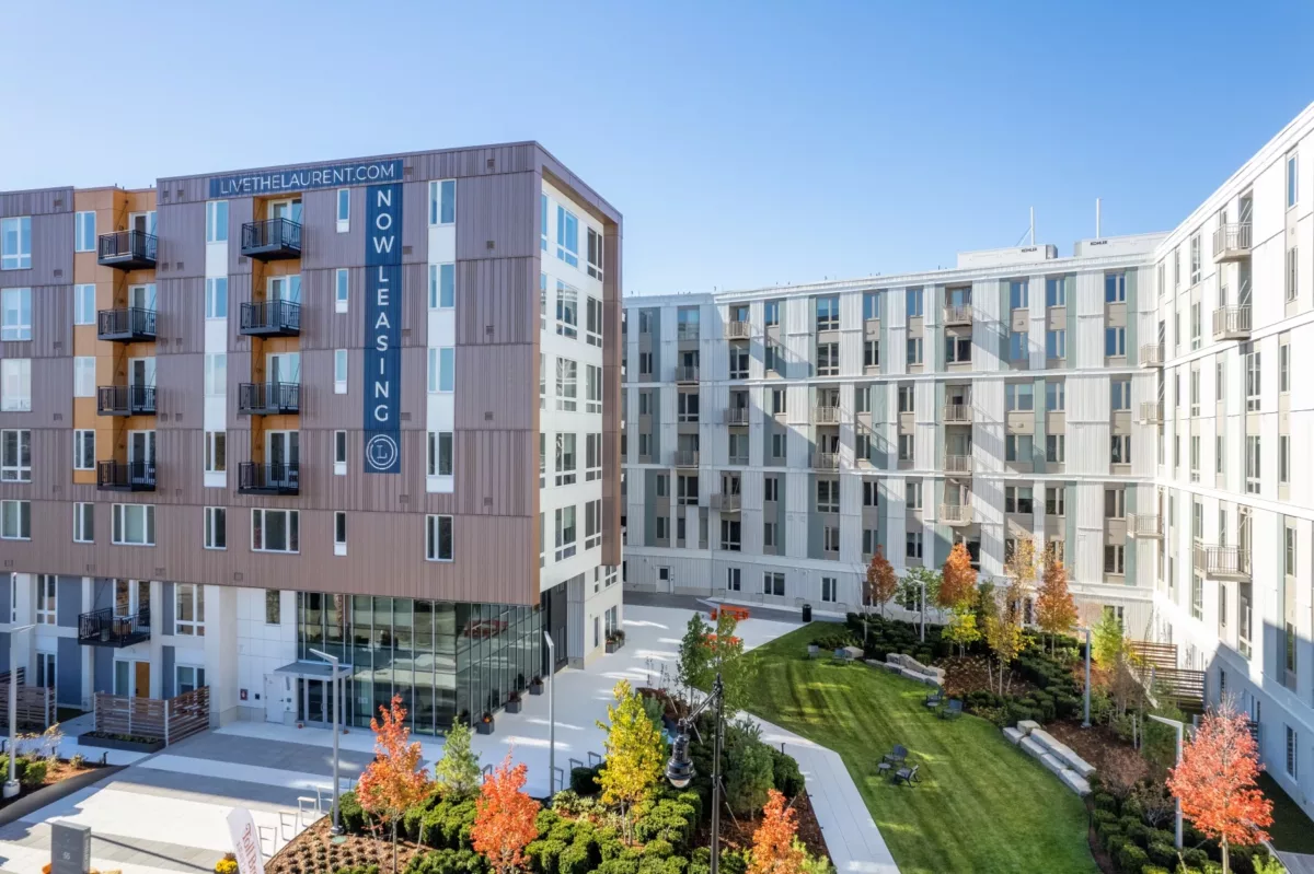 Modern apartment building with landscaped courtyard, walkways, and surrounding residential towers.