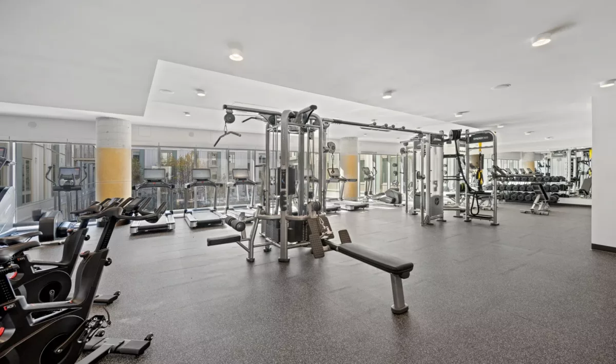 Fitness center with weight machines, benches, and mirrored walls.