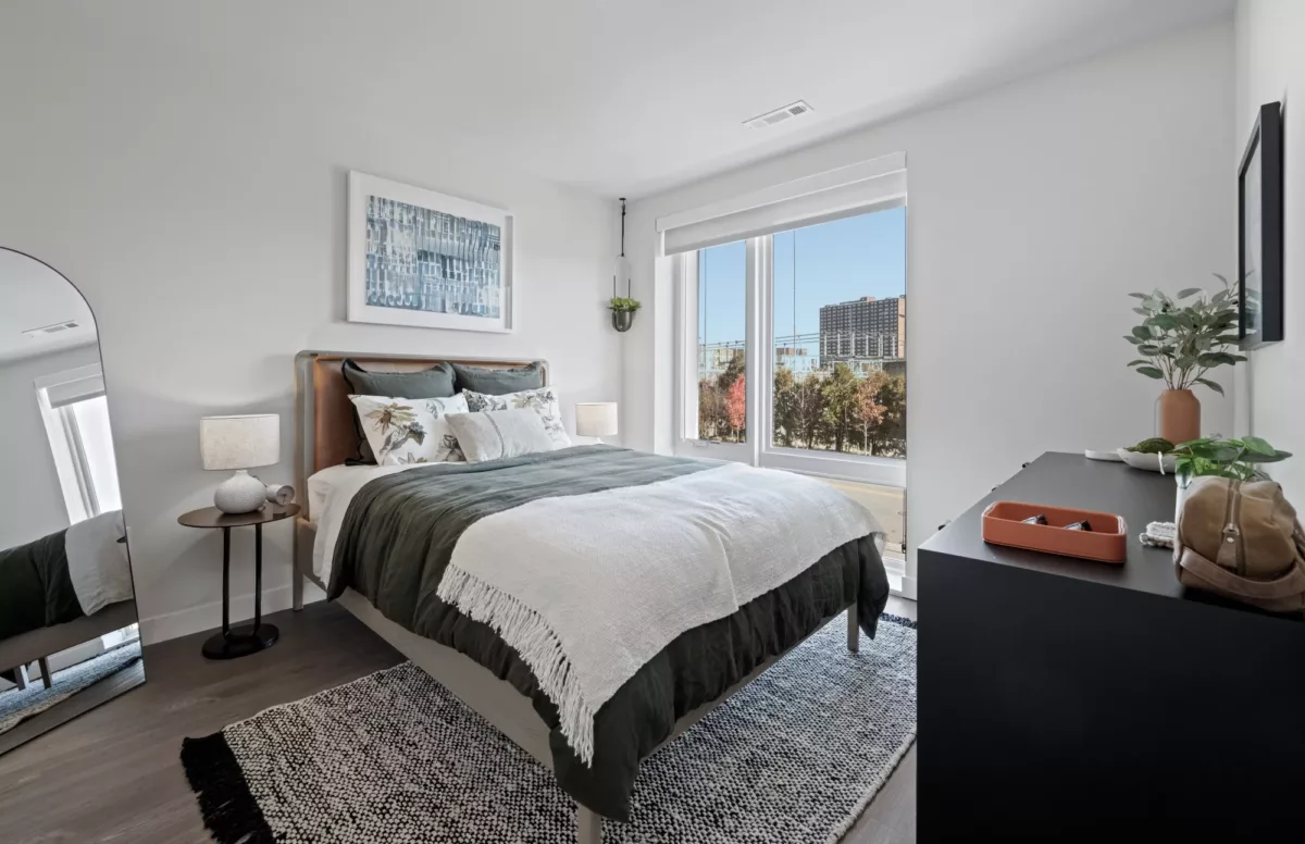 Bedroom with upholstered bed, neutral bedding, and large window for natural light.