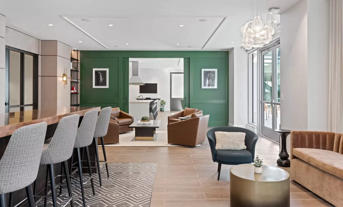 Resident lounge with seating areas, accent chairs, and green feature wall.
