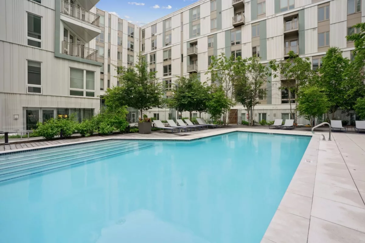 Outdoor pool courtyard with lounge seating and surrounding apartment buildings.