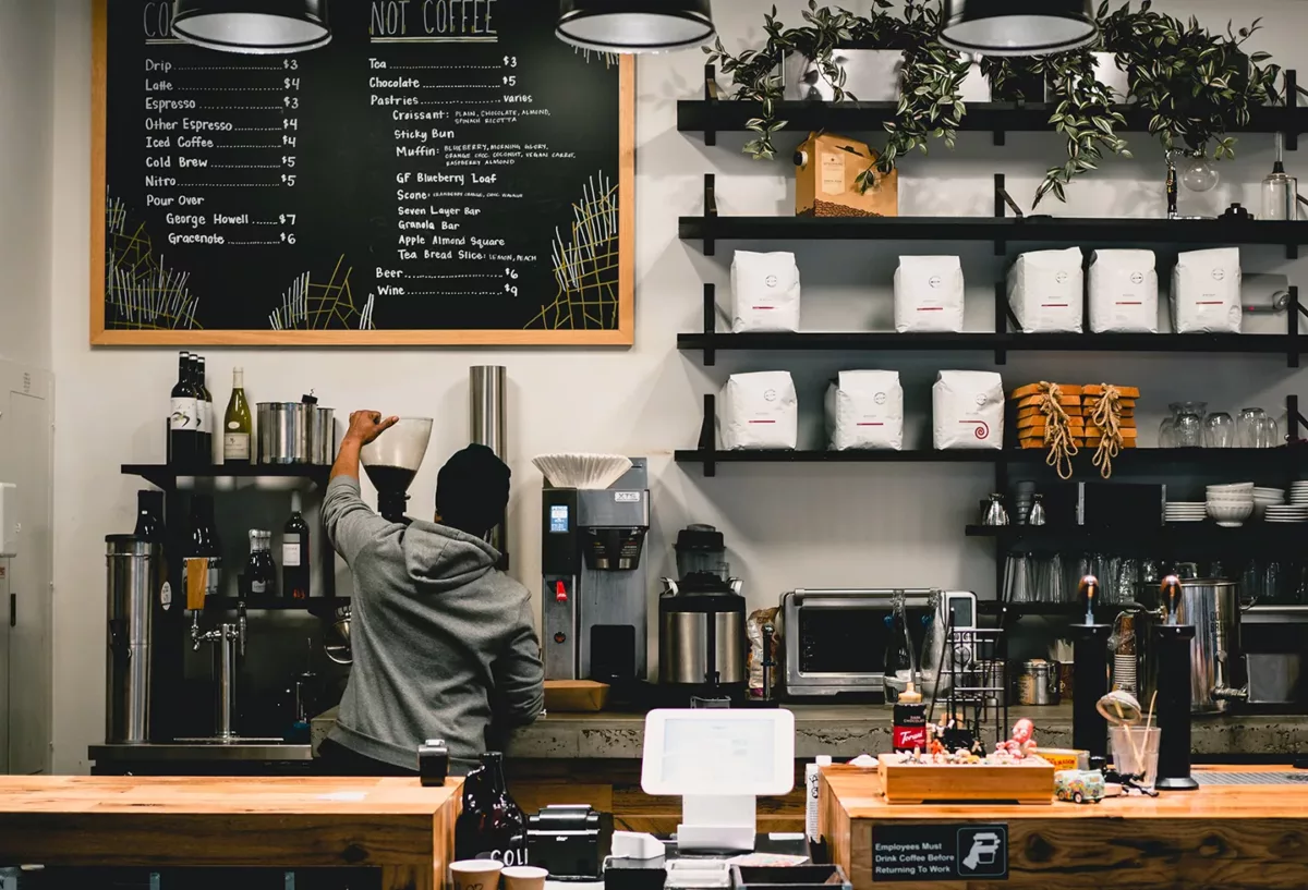 Coffee shop interior with counter seating, shelves, and menu boards.